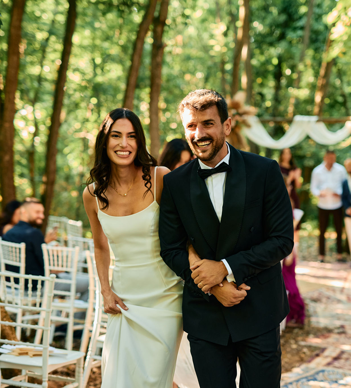 Bride and groom walking in forest ceremony.