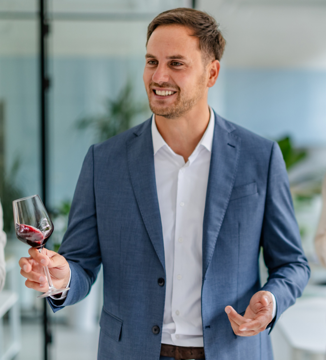 Man in suit holding a wine glass.