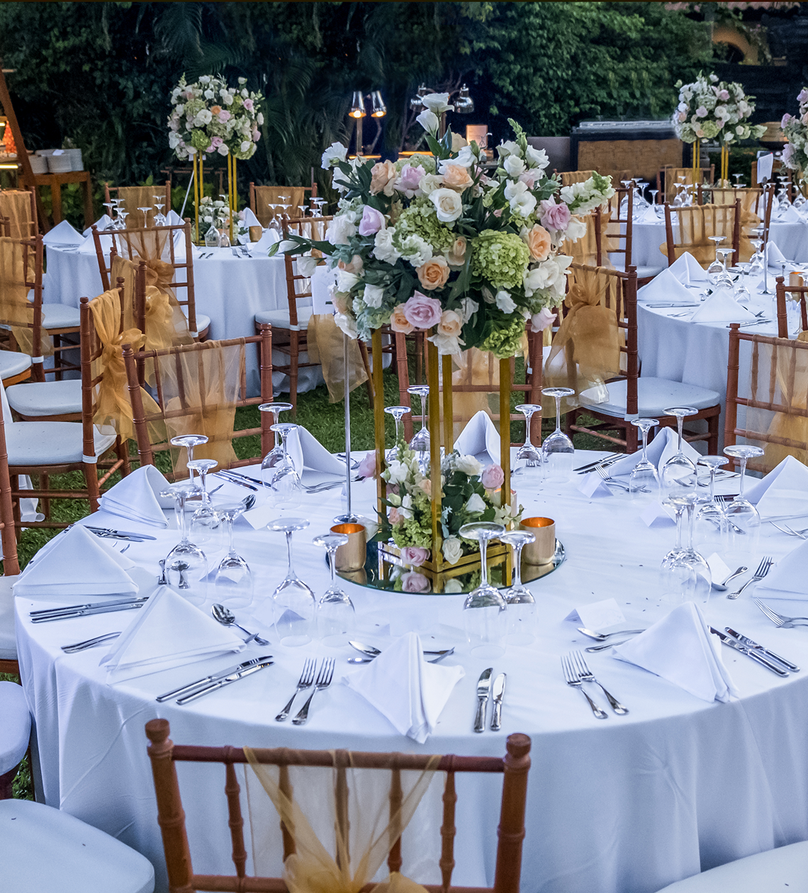 Elegant outdoor wedding reception with floral centerpieces.